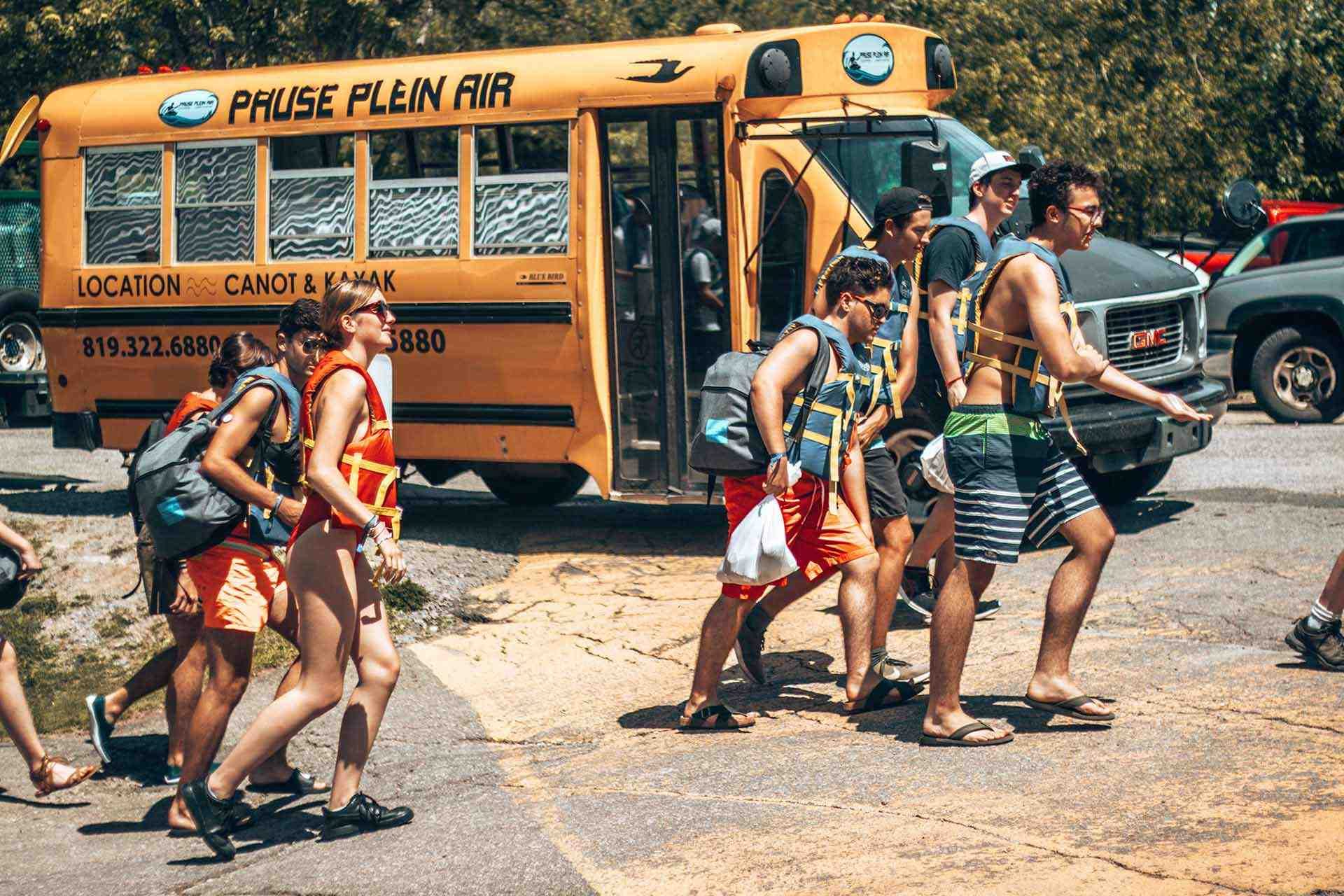 Jeunes adultes en maillots de bain passant devant un autobus scolaire